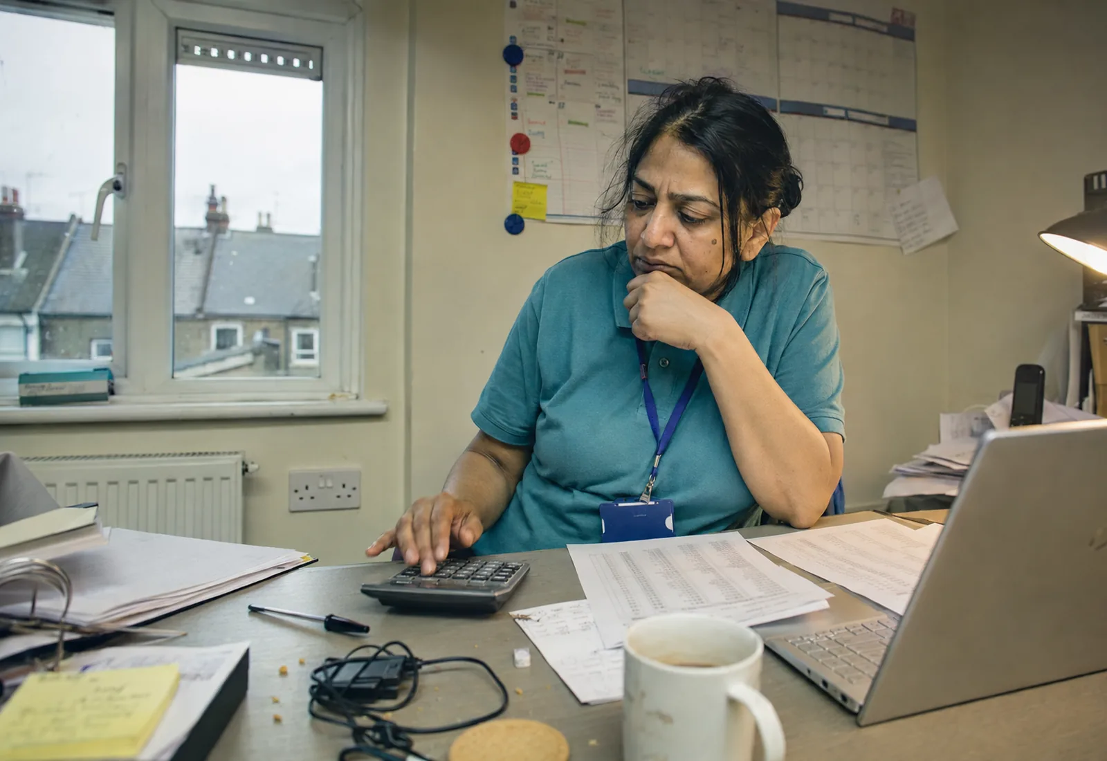 A care agency manager at her desk comparing printed software price quotations.