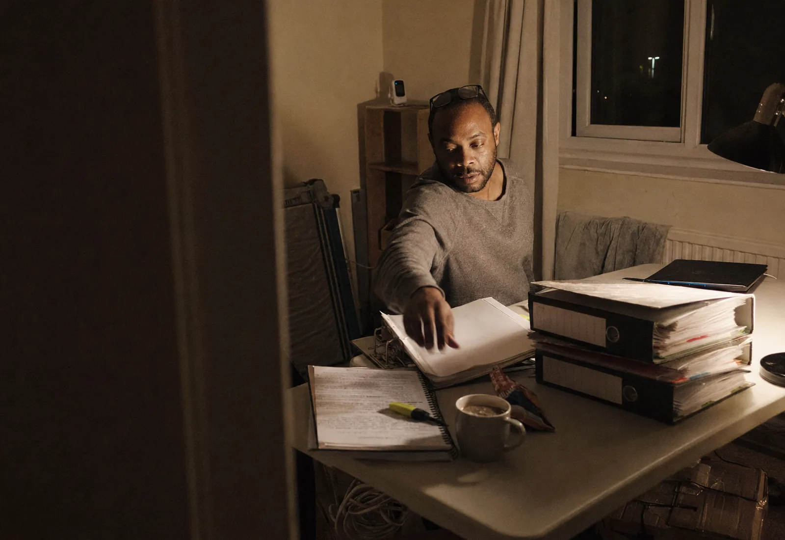 A new care provider working late on registration paperwork at a home office desk.
